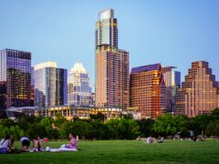 People enjoying a sunny day having picnics at the park with Austin's city in the background